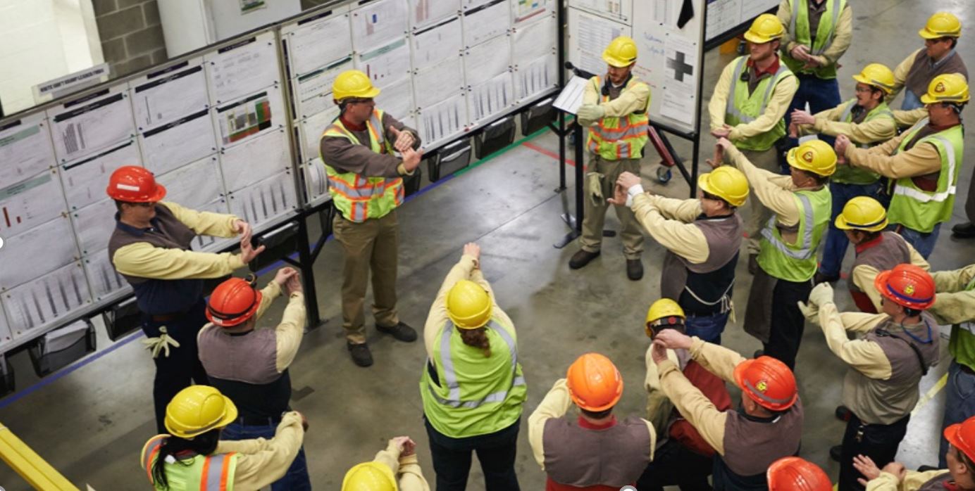 Team gathered for a daily lean management meeting around visual boards